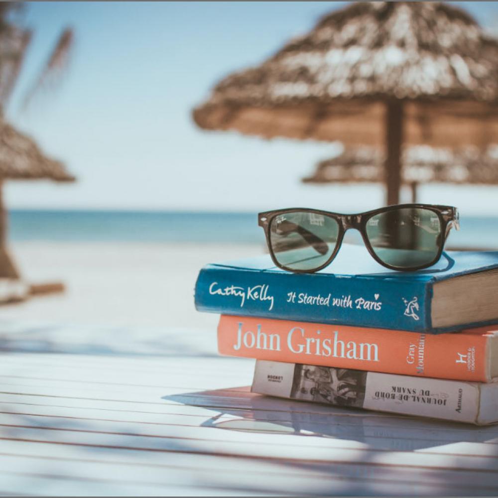 Sunglasses and Book stacked on the beach