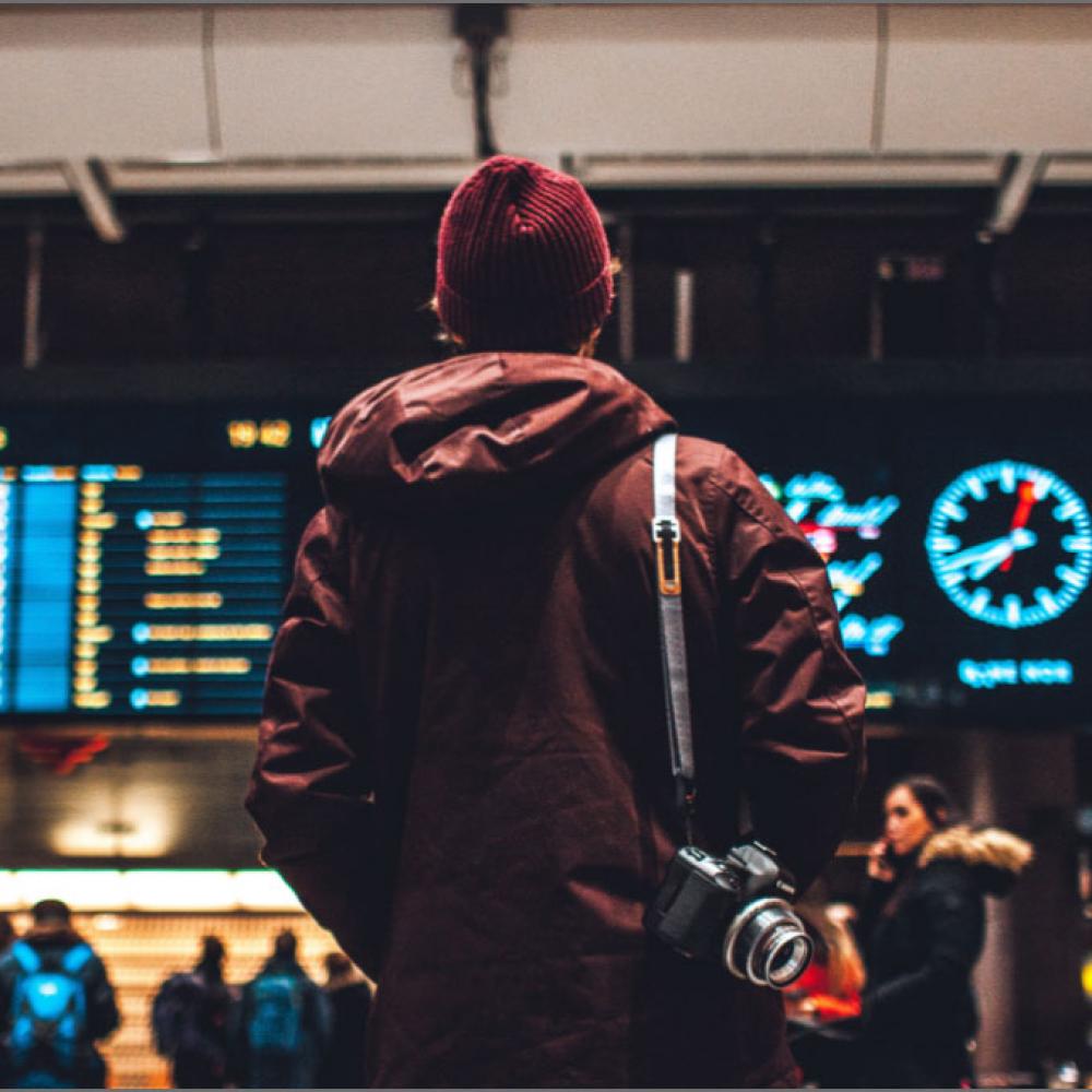 A teenager waiting in an airport looking at flight times