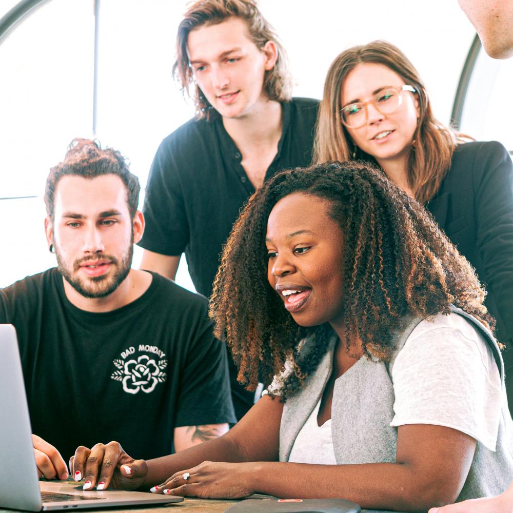 A young tech company gathered around a computer