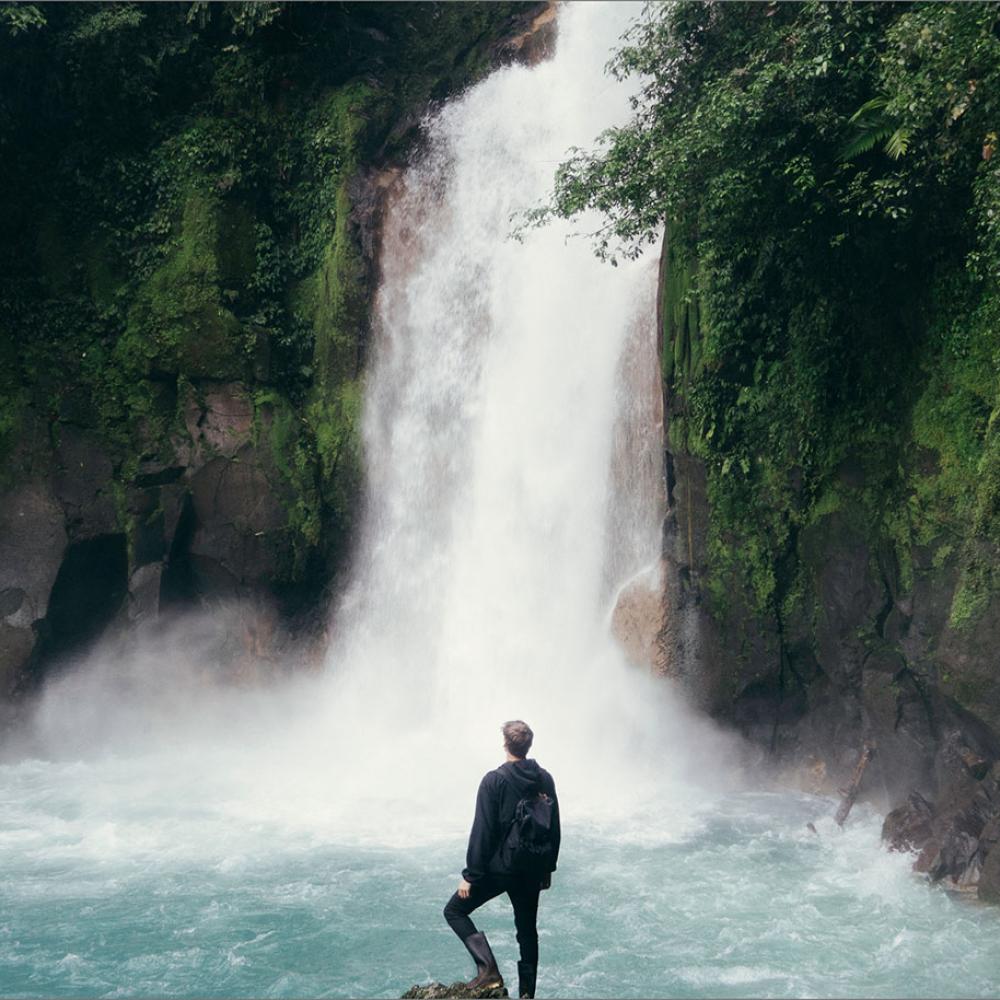 A man standing in front of a waterfall