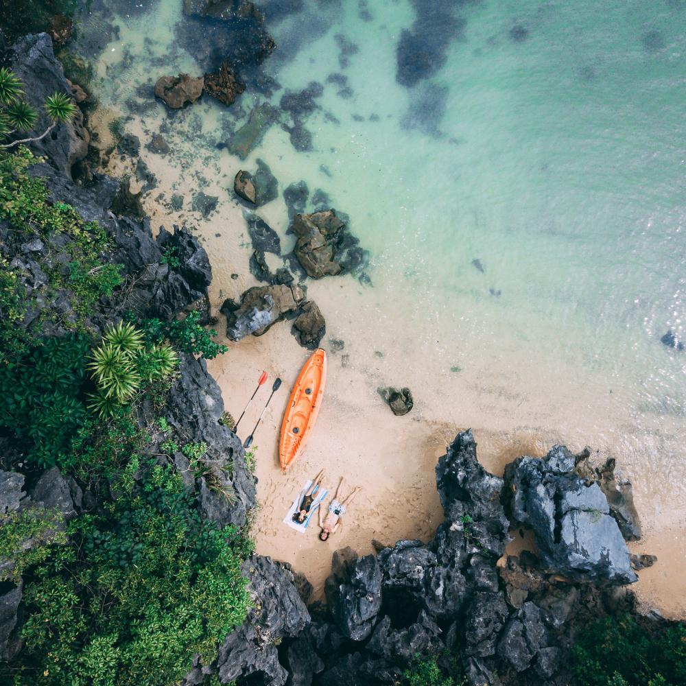 A Couple sitting on a beach overlooking clear water