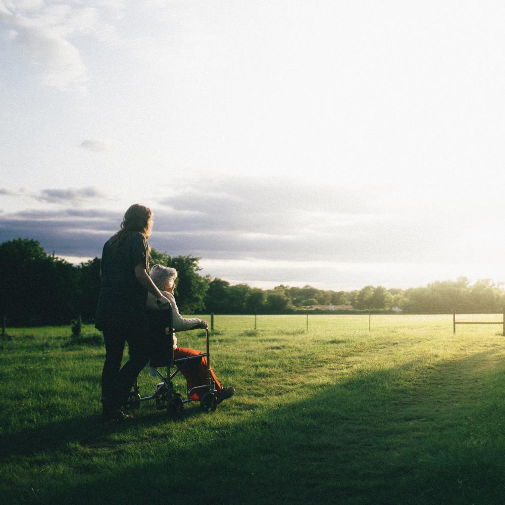A mother and daughter sitting in the field watching the sunset